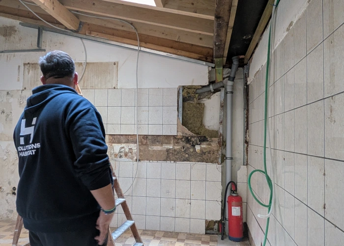 Dégâts des eaux sur un mur avec carrelage décollé et traces d'humidité